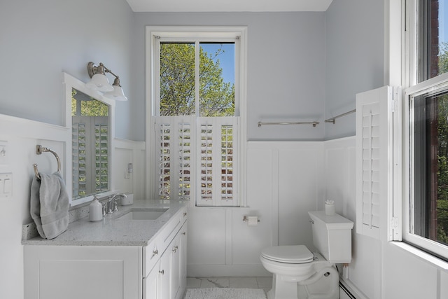 28 Ingalls Rd Unit 28, Portland, ME 04109 - bathroom featuring a decorative wall, wainscoting, toilet, vanity, and a baseboard radiator