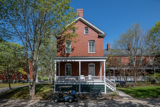 28 Ingalls Rd Unit 28, Portland, ME 04109 - view of front of house with covered porch, a chimney, brick siding, and a front lawn
