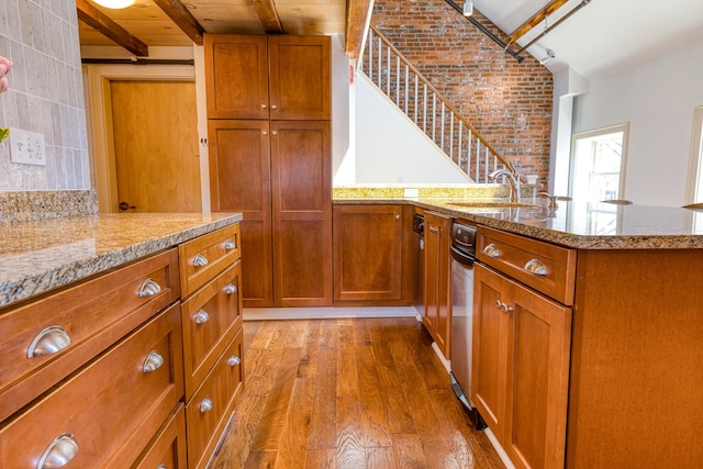 32 Pleasant St Unit 3, Portland, ME 04101 - kitchen with a sink, brown cabinets, wood finished floors, a peninsula, and beamed ceiling