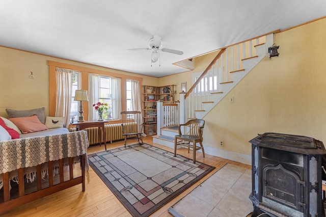 103 Green St, Augusta, ME 04330 - living room featuring a wood stove, radiator heating unit, ceiling fan, stairs, and wood finished floors