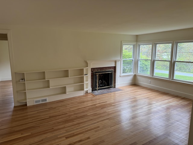 24 Chapel St, Boothbay, ME 04537 - unfurnished living room with wood finished floors, baseboards, and a brick fireplace