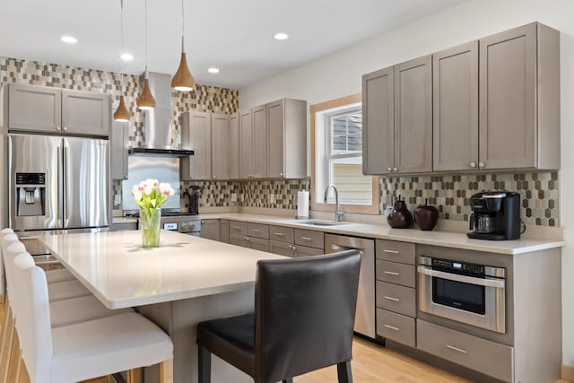 64 Old Kings Hwy, Ogunquit, ME 03907 - kitchen featuring a sink, wall chimney exhaust hood, appliances with stainless steel finishes, gray cabinets, and a kitchen breakfast bar