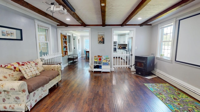 37 Enfield Rd, Lincoln, ME 04457 - living room featuring a wood stove, beam ceiling, hardwood / wood-style floors, a baseboard heating unit, and baseboards