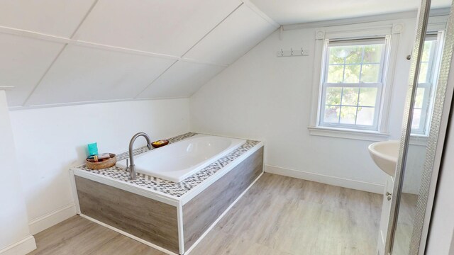 37 Enfield Rd, Lincoln, ME 04457 - full bathroom featuring wood finished floors, lofted ceiling, a bath, and baseboards