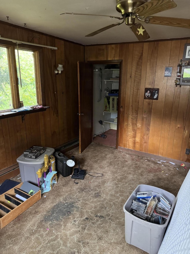 carpeted spare room with wood walls and ceiling fan