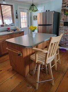 15 River Rd, Phillips, ME 04966 - kitchen featuring freestanding refrigerator, light wood-style flooring, brown cabinets, a center island, and a breakfast bar