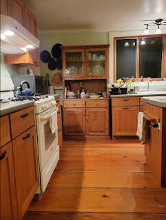 15 River Rd, Phillips, ME 04966 - kitchen featuring gas range gas stove, under cabinet range hood, light wood finished floors, brown cabinetry, and glass insert cabinets