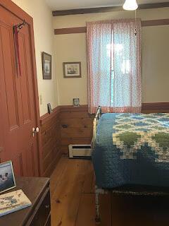 15 River Rd, Phillips, ME 04966 - bedroom featuring a baseboard radiator, a wainscoted wall, wood finished floors, and a ceiling fan