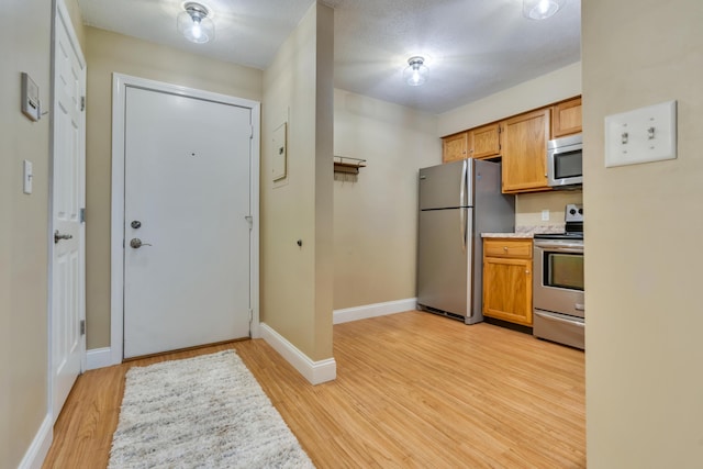 18 Smithwheel Rd Unit 21, Old Orchard Beach, ME 04064 - kitchen with appliances with stainless steel finishes, light wood finished floors, baseboards, light countertops, and brown cabinets