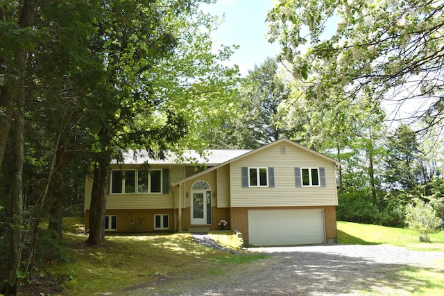 96 Pamela Dr, Winthrop, ME 04364 - raised ranch featuring gravel driveway, a garage, brick siding, and a front yard