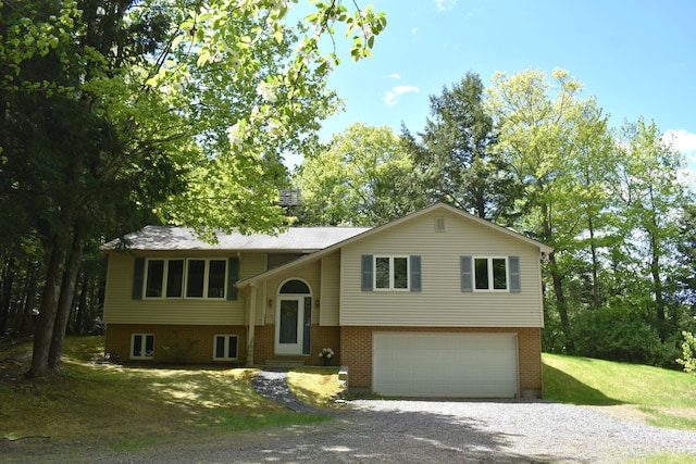 96 Pamela Dr, Winthrop, ME 04364 - raised ranch with gravel driveway, a garage, a front yard, and brick siding