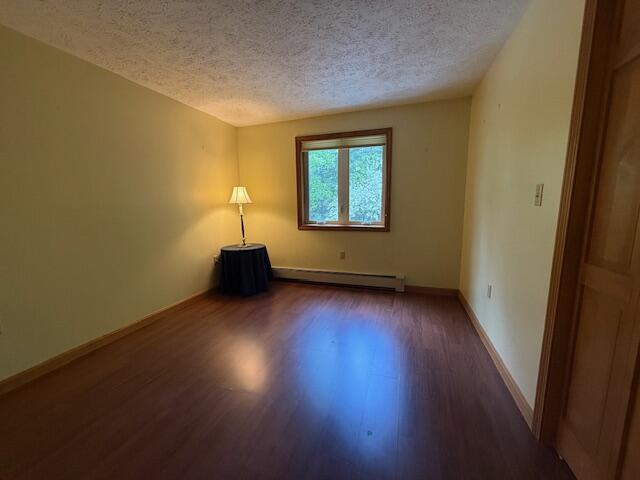 96 Pamela Dr, Winthrop, ME 04364 - empty room with wood finished floors, a baseboard radiator, a textured ceiling, and baseboards