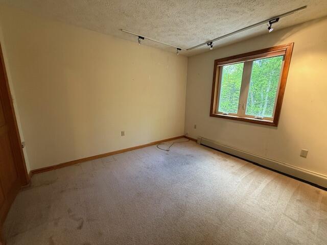 96 Pamela Dr, Winthrop, ME 04364 - empty room with track lighting, baseboard heating, light carpet, a textured ceiling, and baseboards