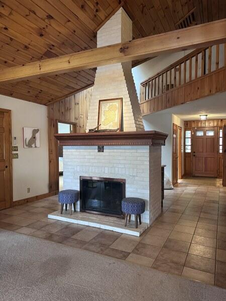 27 Chickadee Ln, Naples, ME 04055 - tiled living room with high vaulted ceiling, a brick fireplace, baseboards, wood ceiling with exposed beams, and carpet flooring