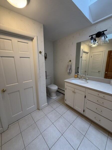 27 Chickadee Ln, Naples, ME 04055 - bathroom featuring tile patterned flooring, a baseboard radiator, a skylight, toilet, and vanity