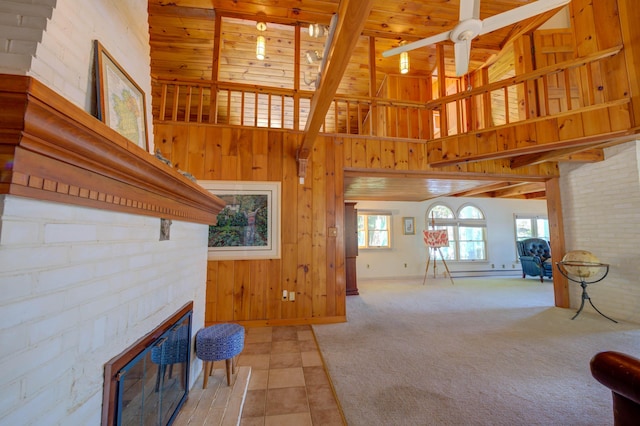 27 Chickadee Ln, Naples, ME 04055 - living area with a glass covered fireplace, wooden walls, wooden ceiling with exposed beams, a high ceiling, and light colored carpet