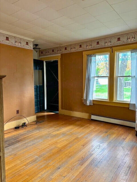 3 King St, Sanford, ME 04083 - spare room featuring a baseboard heating unit, hardwood / wood-style floors, baseboards, and crown molding