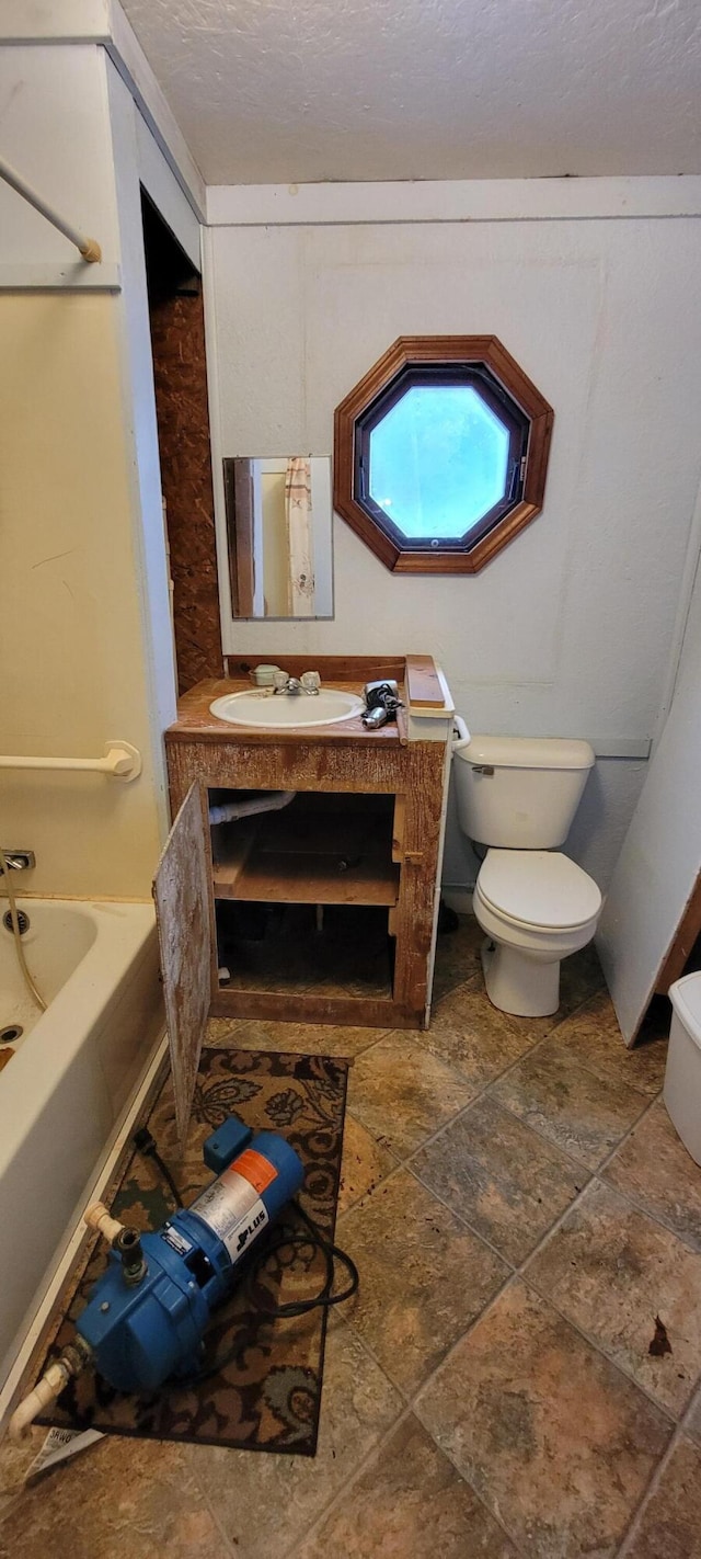 208 Camp Rd, Cooper, ME 04657 - bathroom with toilet, a tub to relax in, stone finish flooring, and vanity
