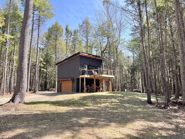 80 Bluejay Ln, Waltham, ME 04605 - view of front facade featuring a wooden deck, a garage, a wooded view, and dirt driveway