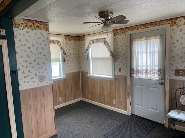 1 S Park St, Caribou, ME 04736 - foyer entrance with wainscoting, a ceiling fan, wooden walls, wallpapered walls, and dark colored carpet