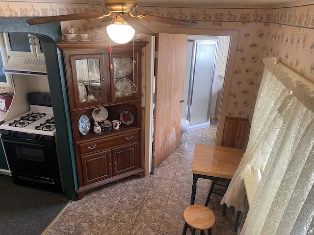1 S Park St, Caribou, ME 04736 - kitchen featuring gas range oven, wall chimney range hood, ceiling fan, and wallpapered walls