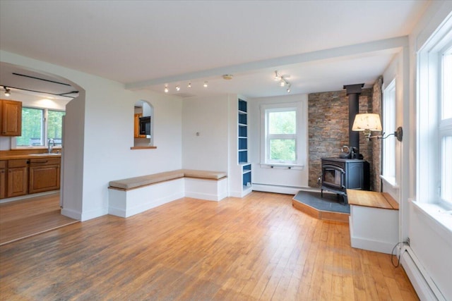 229 Choate Rd, Montville, ME 04941 - unfurnished living room featuring a baseboard heating unit, light wood-style floors, a sink, a wood stove, and plenty of natural light