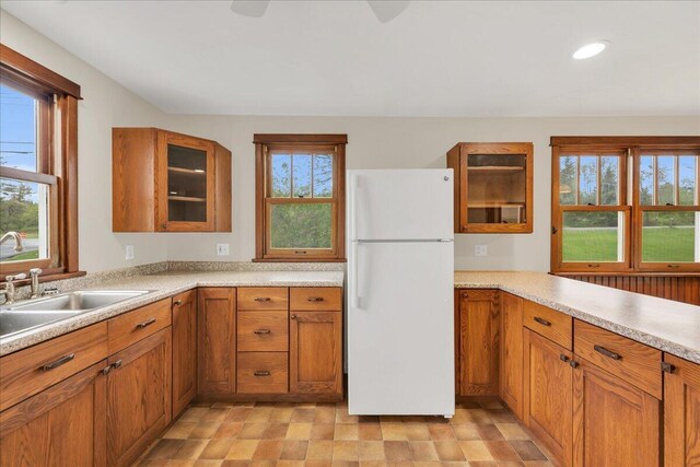 626 Main Rd, Eddington, ME 04428 - kitchen featuring freestanding refrigerator, a sink, brown cabinetry, light countertops, and glass insert cabinets