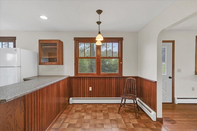 626 Main Rd, Eddington, ME 04428 - unfurnished dining area featuring a baseboard radiator, wainscoting, arched walkways, and wooden walls
