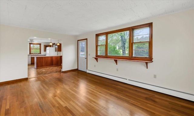 626 Main Rd, Eddington, ME 04428 - unfurnished living room featuring a baseboard radiator, wood finished floors, plenty of natural light, and baseboards