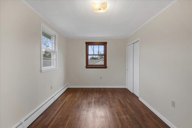626 Main Rd, Eddington, ME 04428 - unfurnished bedroom featuring wood finished floors, multiple windows, a baseboard heating unit, baseboards, and crown molding