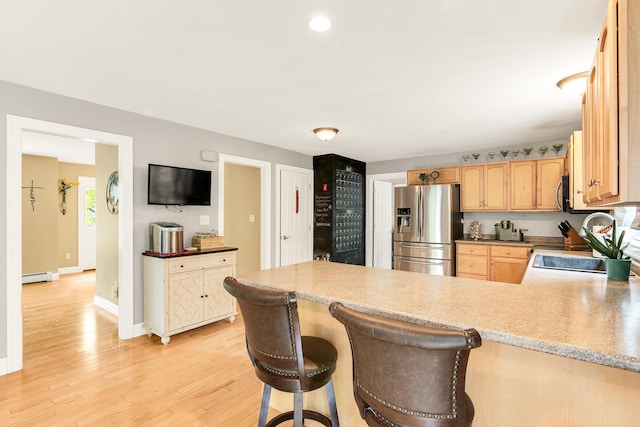77 Cemetery Rd, Berwick, ME 03901 - kitchen with stainless steel appliances, a baseboard radiator, a peninsula, light brown cabinetry, and light wood-type flooring