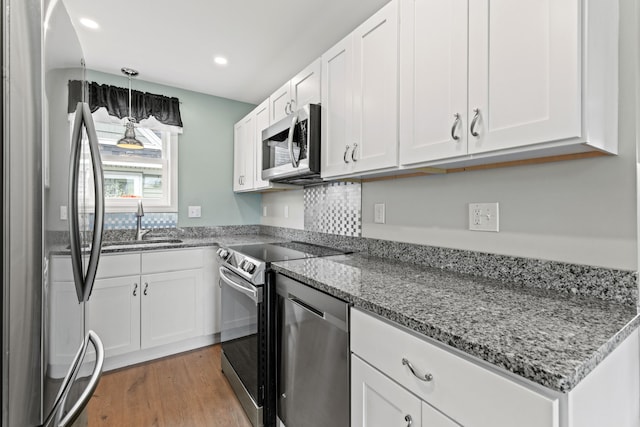 994 Portland Rd Unit 30, Saco, ME 04072 - kitchen with stainless steel appliances, a sink, white cabinets, light stone countertops, and light wood-type flooring