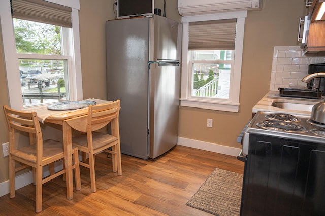 750 Roosevelt Trl Unit 7, Naples, ME 04055 - kitchen with freestanding refrigerator, a wall mounted AC, range with electric stovetop, light wood finished floors, and a sink