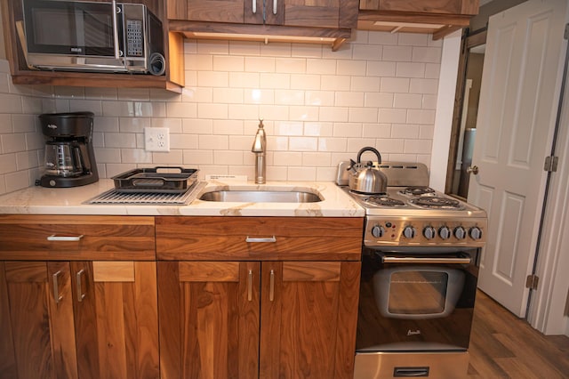 750 Roosevelt Trl Unit 7, Naples, ME 04055 - kitchen featuring appliances with stainless steel finishes, brown cabinetry, tasteful backsplash, a sink, and dark wood-style flooring