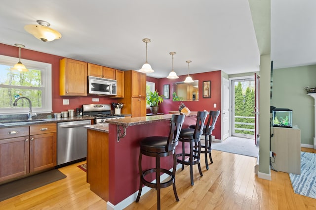 455 Duck Pond Rd, Westbrook, ME 04092 - kitchen with stainless steel appliances, a sink, light wood finished floors, and a breakfast bar