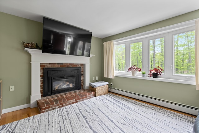 455 Duck Pond Rd, Westbrook, ME 04092 - living area featuring a baseboard heating unit, a fireplace, wood finished floors, and baseboards