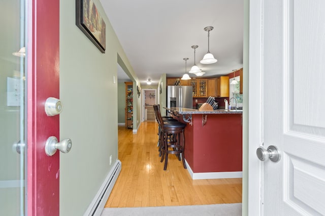 455 Duck Pond Rd, Westbrook, ME 04092 - kitchen with stainless steel fridge with ice dispenser, light wood finished floors, a baseboard radiator, glass insert cabinets, and a breakfast bar area