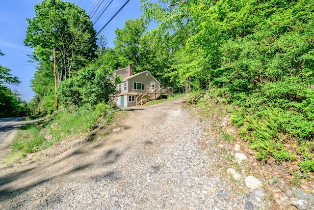 148 Naples Rd, Harrison, ME 04040 - obstructed view of property featuring gravel driveway, stairway, a deck, and a chimney