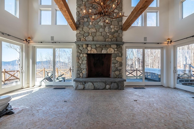6065 Sandy River Cir, Carrabassett Valley, ME 04947 - unfurnished living room featuring a towering ceiling, plenty of natural light, a stone fireplace, and beam ceiling