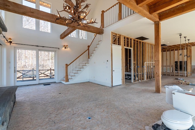 6065 Sandy River Cir, Carrabassett Valley, ME 04947 - unfurnished living room with a high ceiling, plenty of natural light, stairway, and a chandelier