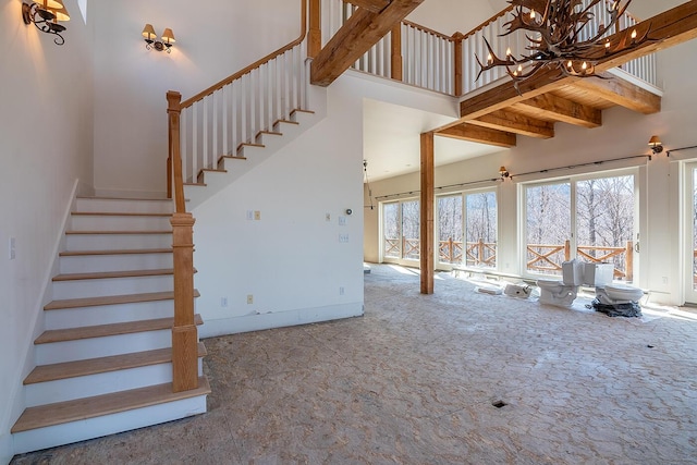 6065 Sandy River Cir, Carrabassett Valley, ME 04947 - unfurnished living room featuring carpet floors, stairs, a towering ceiling, a chandelier, and baseboards