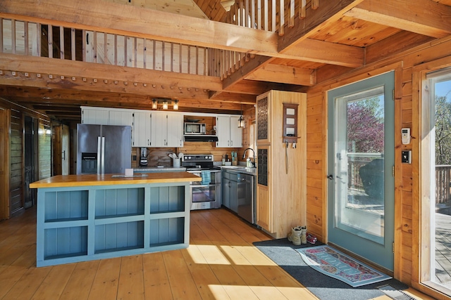 658 High St, West Gardiner, ME 04345 - kitchen featuring stainless steel appliances, white cabinets, beam ceiling, a kitchen island, and wood walls