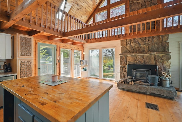 658 High St, West Gardiner, ME 04345 - kitchen featuring butcher block counters, open floor plan, light wood-type flooring, a stone fireplace, and a center island