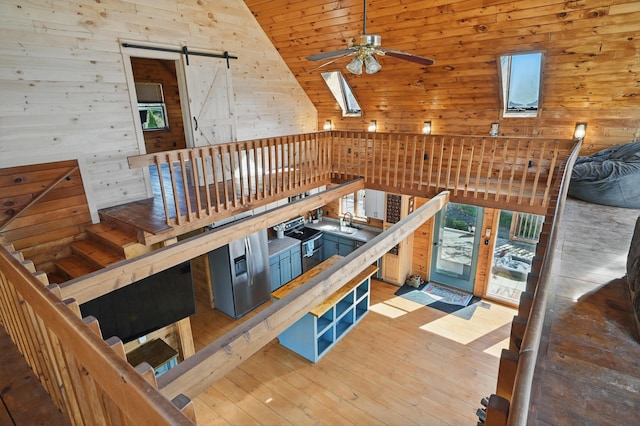 658 High St, West Gardiner, ME 04345 - unfurnished living room featuring a ceiling fan, a sink, wood walls, hardwood / wood-style flooring, and a barn door