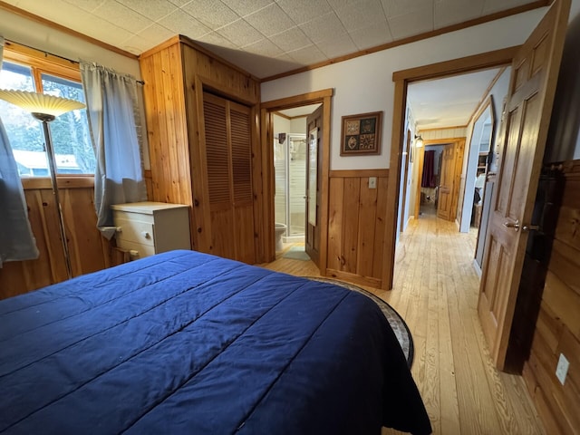 17 Macallister Cove Rd, Orient, ME 04471 - bedroom with wooden walls, light wood-type flooring, crown molding, ensuite bathroom, and a wainscoted wall