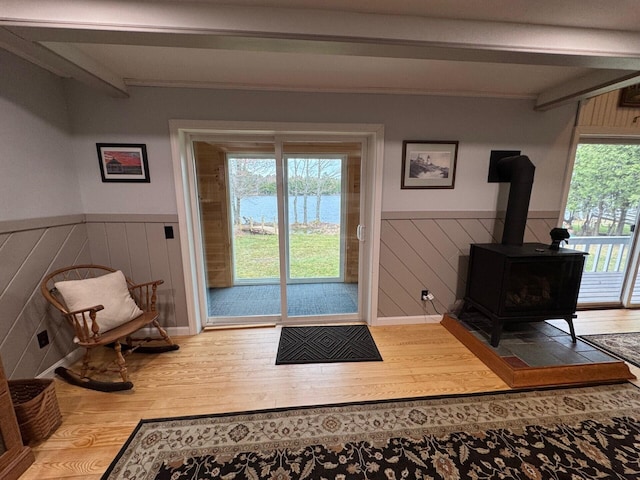 17 Macallister Cove Rd, Orient, ME 04471 - doorway to outside featuring wood finished floors, beamed ceiling, wainscoting, a wood stove, and a water view