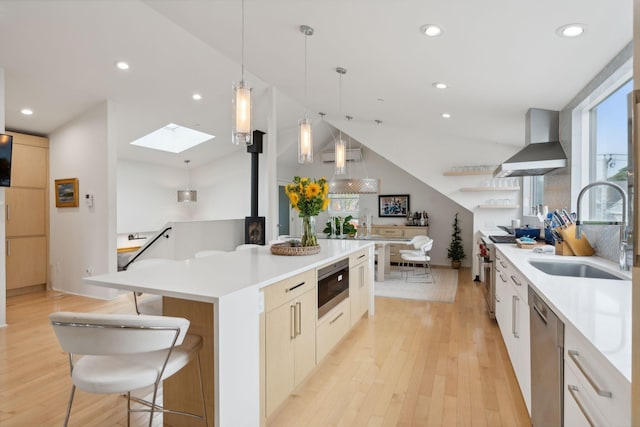123 Cumberland Ave, Portland, ME 04101 - kitchen featuring wall chimney range hood, a sink, appliances with stainless steel finishes, a skylight, and a wood stove