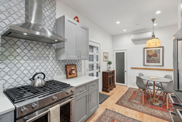 123 Cumberland Ave, Portland, ME 04101 - kitchen with wall chimney exhaust hood, gas range, gray cabinetry, light countertops, and tasteful backsplash