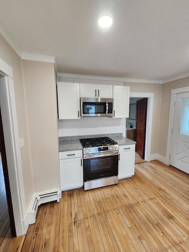 76 Somerset St, Millinocket, ME 04462 - kitchen with stainless steel appliances, a baseboard heating unit, light wood finished floors, white cabinetry, and crown molding