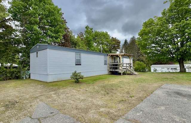 manufactured / mobile home featuring a front yard and view of wooded area